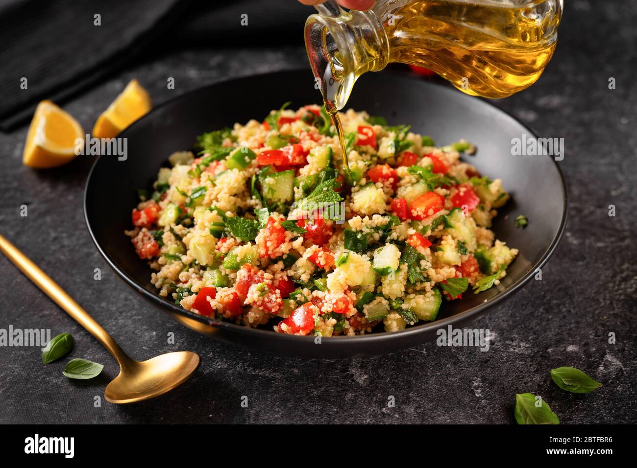 Verser une huile d'olive dans un plat avec des légumes frais salade de couscous Banque D'Images