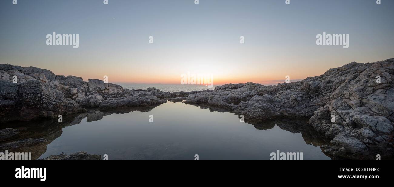 Coucher de soleil sur une plage rocheuse avec reflet de l'eau Banque D'Images