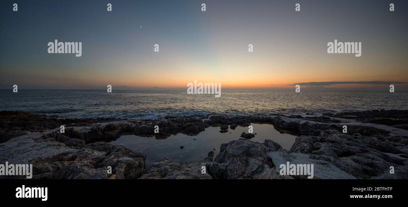 Coucher de soleil sur une plage rocheuse avec reflet de l'eau Banque D'Images