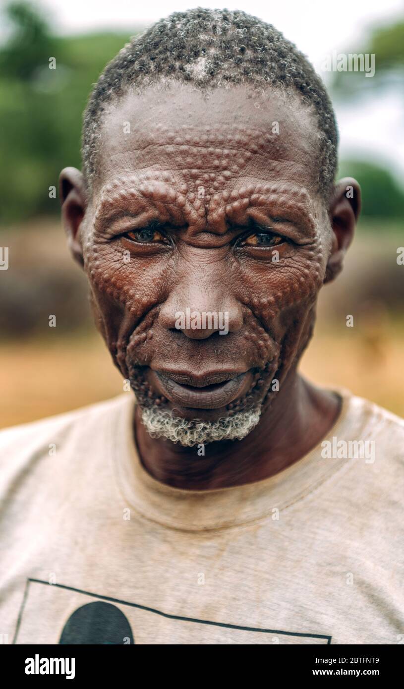 Tribu TOPOSA, SOUDAN DU SUD - 12 MARS 2020 : homme âgé en t-shirt sale et avec des cicatrices traditionnelles sur le visage regardant la caméra tout en vivant à Toposa Banque D'Images