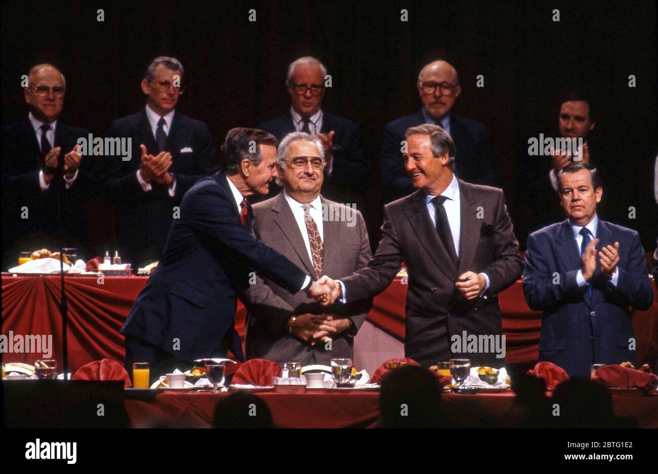Le président George Bush se serre la main avec Jerry Weintraub après avoir pris la parole devant des membres de l'Académie des arts et des sciences de la télévision à Los Angeles, vers les années 1990 Banque D'Images