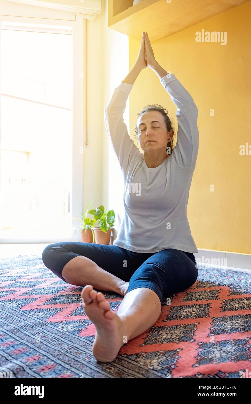 Jolie fille espagnole faisant du yoga à la maison dans le salon Banque D'Images