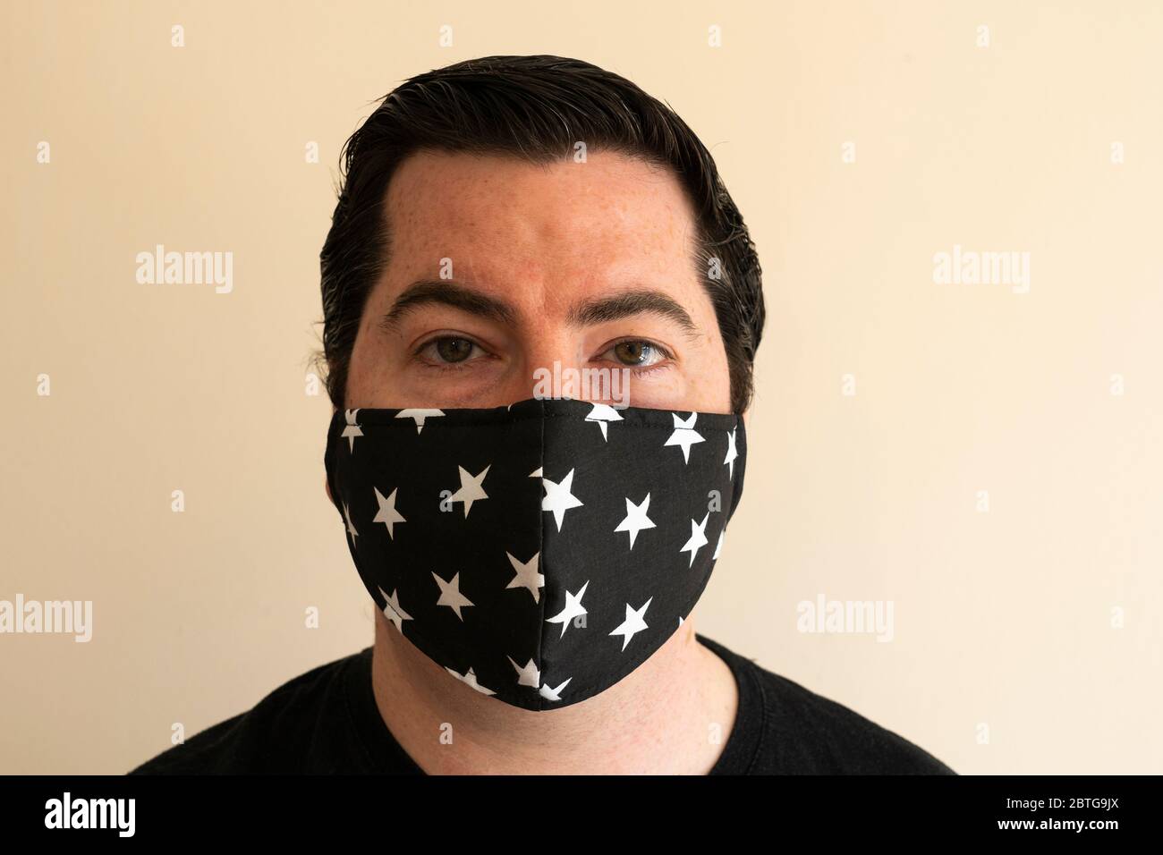 Un homme de la fin de la trentaine avec un masque réutilisable sur son nez et sa bouche, regardant directement le spectateur pendant la pandémie du coronavirus Covid 19 Banque D'Images