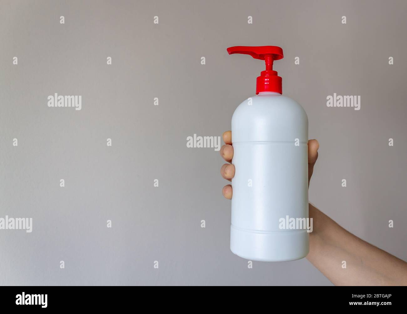 Bouteille de pompe en plastique blanc isolée sur fond blanc, la femme tient une bouteille en plastique dans sa main. Zone de texte publicitaire de l'espace de copie Banque D'Images