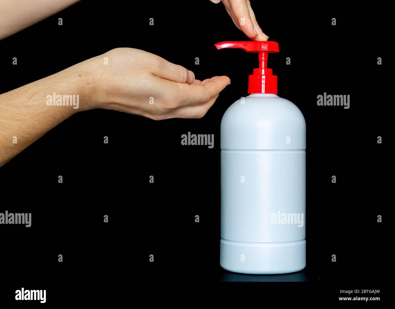 Flacon de pompe de poussée en plastique blanc isolé sur fond noir, femme mains poussant flacon de pompe. Zone de texte publicitaire de l'espace de copie Banque D'Images