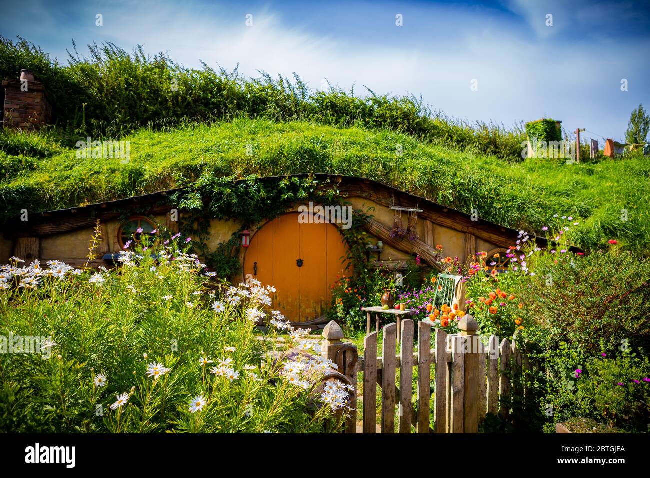 Un trou hobbit avec une porte orange au film Hobbiton près de Matamata, Nouvelle-Zélande, par une journée ensoleillée Banque D'Images