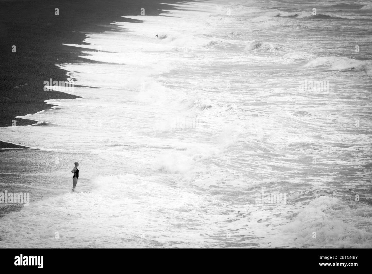 Femme debout au bord d'une mer rugueuse à Brighton Banque D'Images