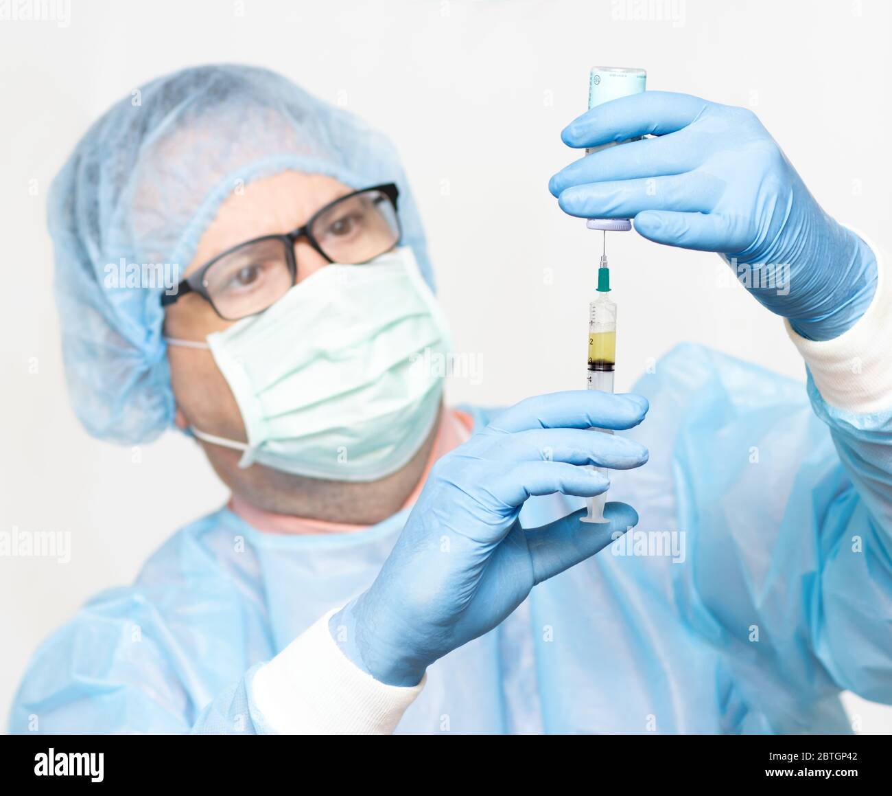 Le médecin prend le médicament d'une bouteille à une injection, se concentre sur les mains, visage flou. Scientifique tenant une seringue et un vaccin. Banque D'Images