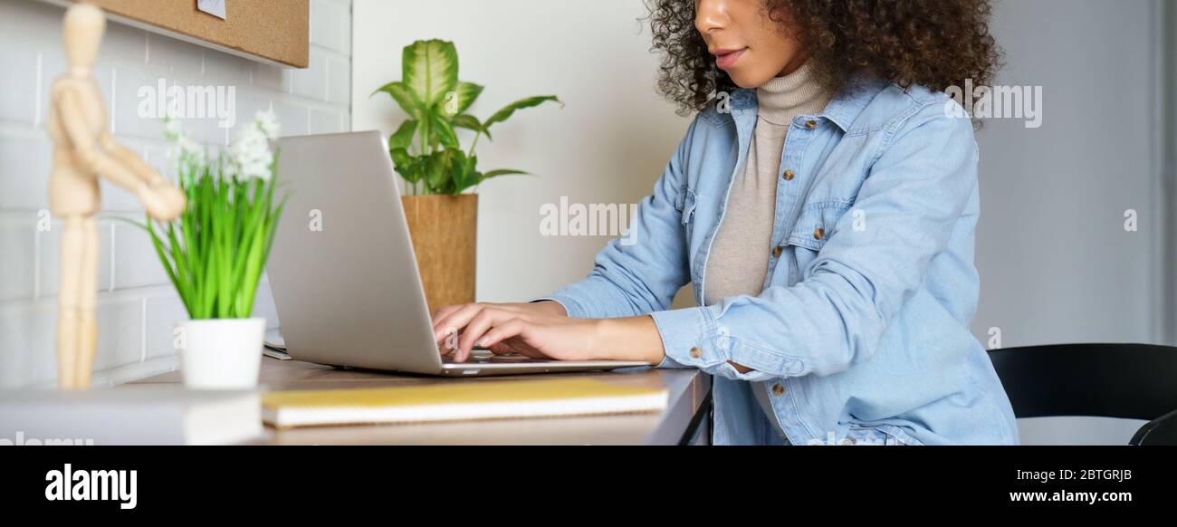 Femme africaine travaillant en ligne à partir de bureau à domicile en utilisant ordinateur portable, bannière. Banque D'Images