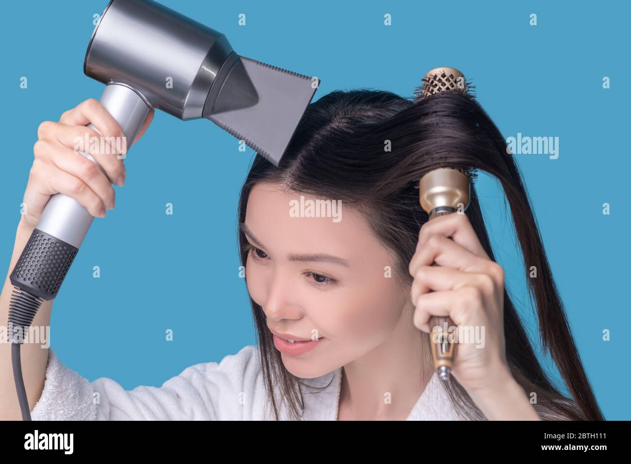 Brunette jeune femme asiatique sèche ses cheveux Banque D'Images