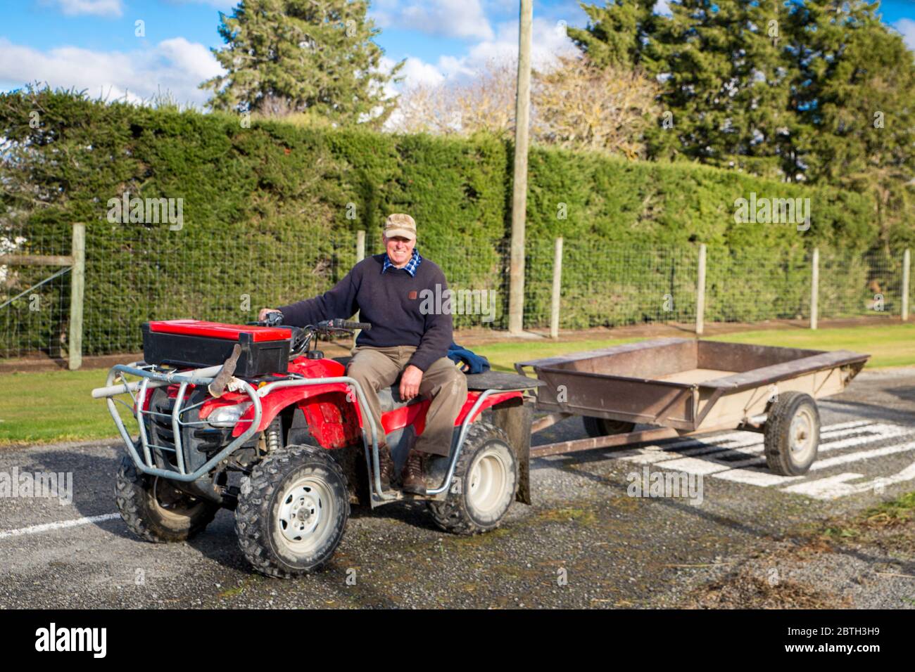 Annat, Canterbury, Nouvelle-Zélande, mai 26 2020 : un agriculteur à la retraite lance une remorque derrière son quad pour recueillir des haies sur une route rurale Banque D'Images
