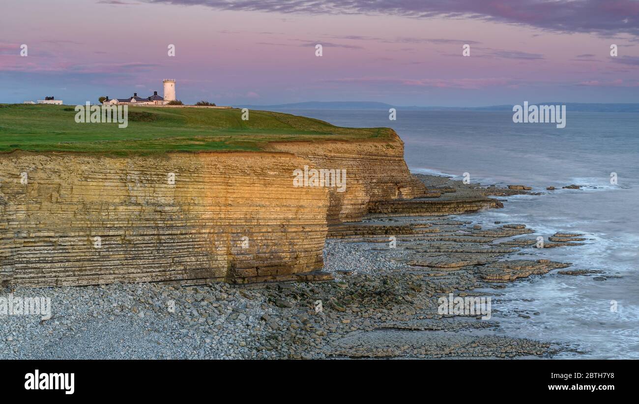 Phare de Nash point, sud du pays de Galles, au coucher du soleil. Le phare est situé au sommet de falaises abruptes, surplombant le canal de Bristol Banque D'Images