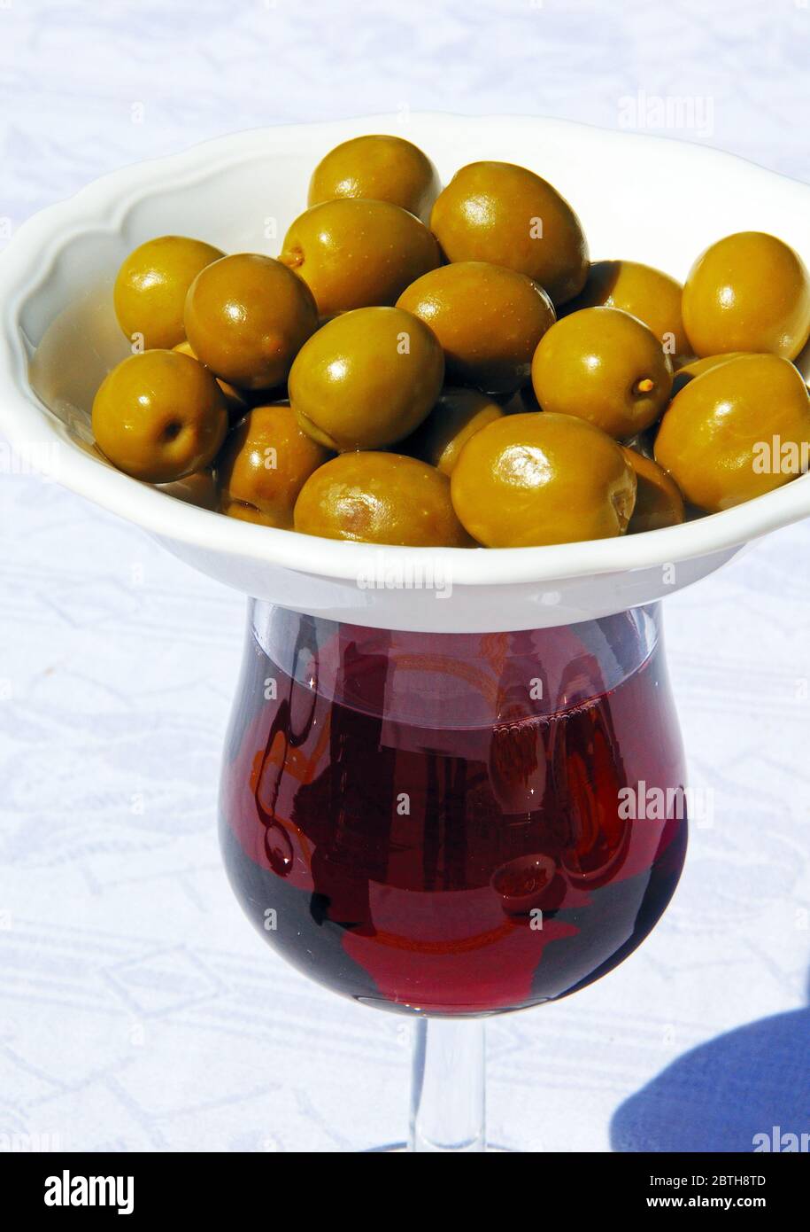 Verre de vin rouge avec plat d'olives vertes sur le dessus pour garder les mouches hors (tapas modernes provient du mot tapa signifiant à couvrir), Espagne. Banque D'Images