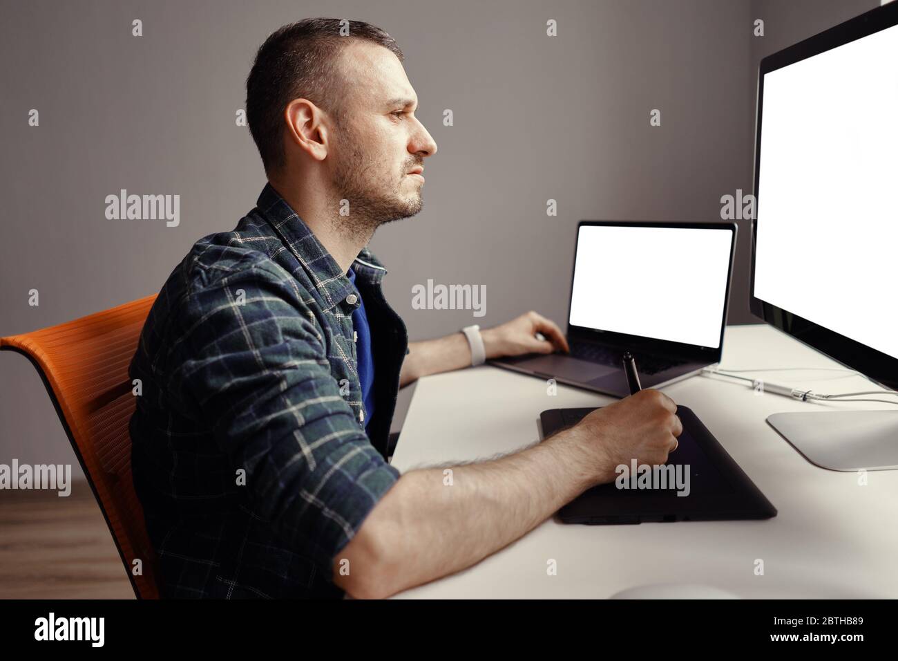 Graphiste travaillant avec un écran interactif à stylet, une tablette de dessin numérique et un stylet sur un ordinateur avec un moniteur vierge Banque D'Images