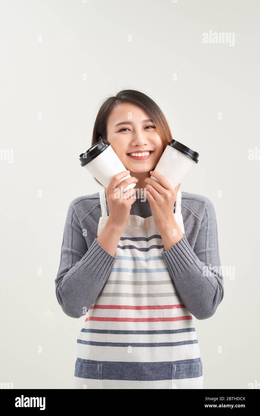 Charmante fille tient une tasse jetable avec des boissons et regarde directement à l'appareil photo isolé sur fond blanc Banque D'Images