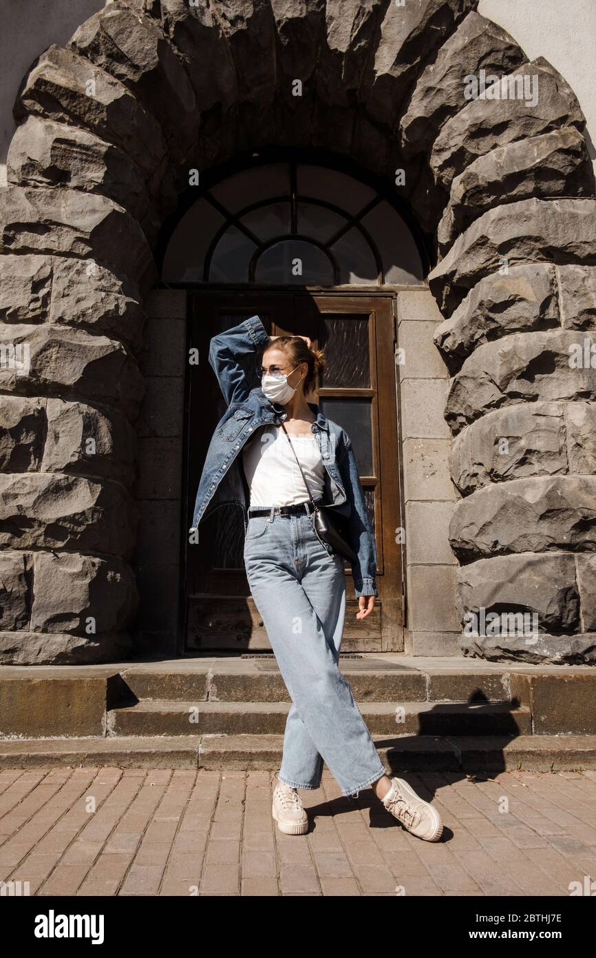 Femme adulte tranquille dans un masque médical de protection dans un vieux bâtiment de rue Banque D'Images