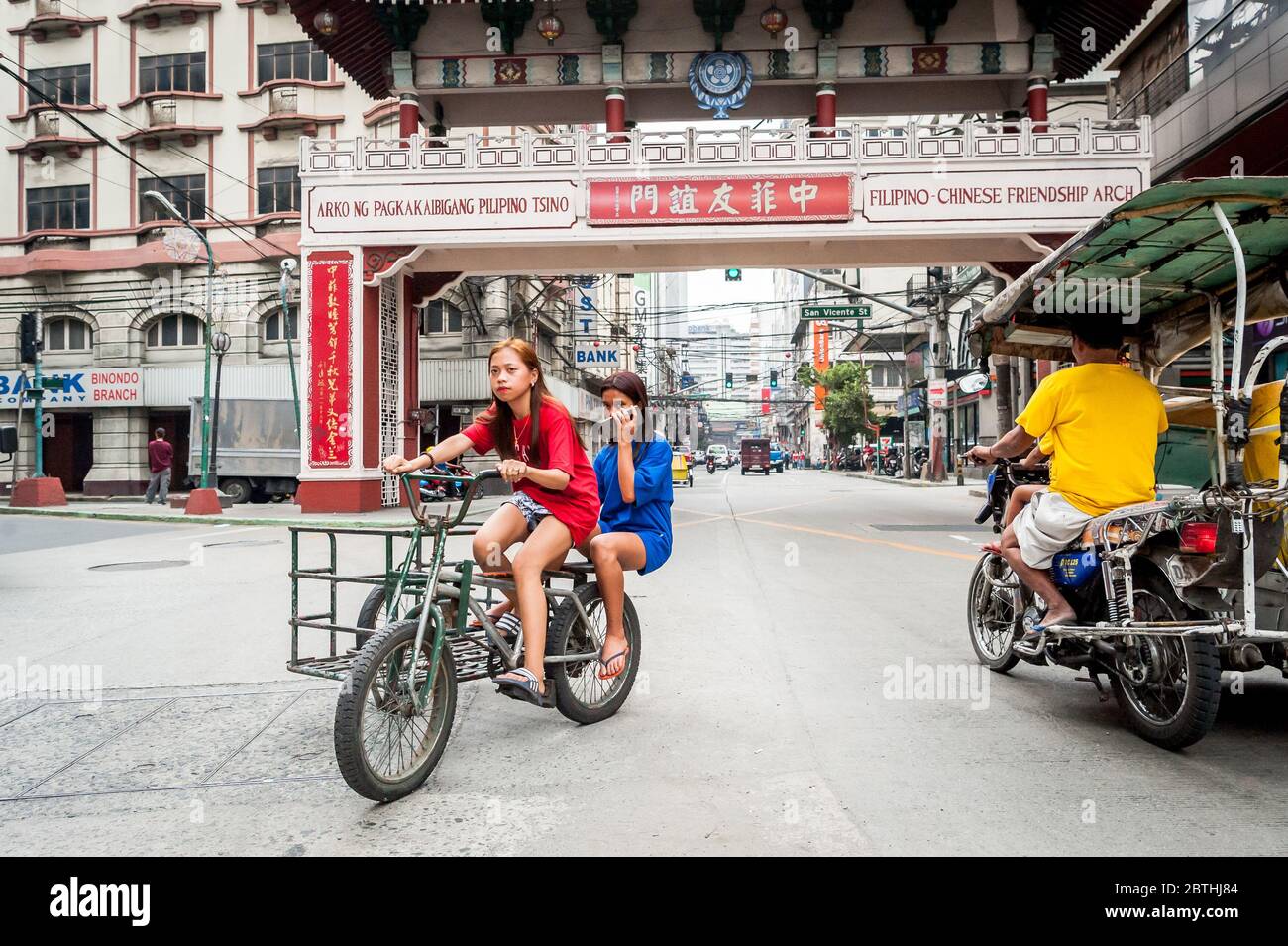 Deux jeunes filles philippines locales traversent la jonction animée de l'Arc d'amitié philippin chinois dans le quartier de Binondo Chinatown à Manille Philippines. Banque D'Images