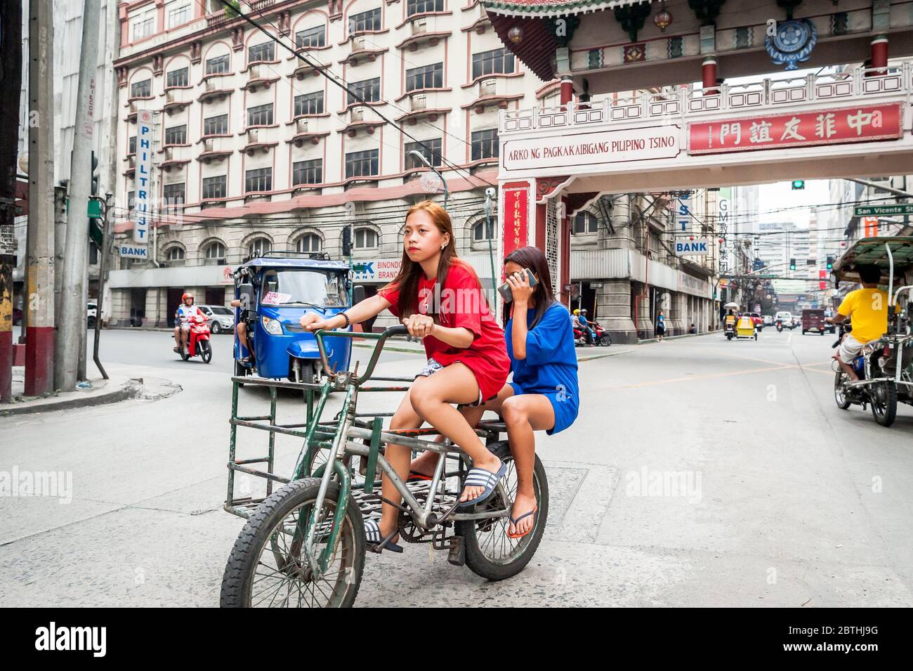 Deux jeunes filles philippines locales traversent la jonction animée de l'Arc d'amitié philippin chinois dans le quartier de Binondo Chinatown à Manille Philippines. Banque D'Images