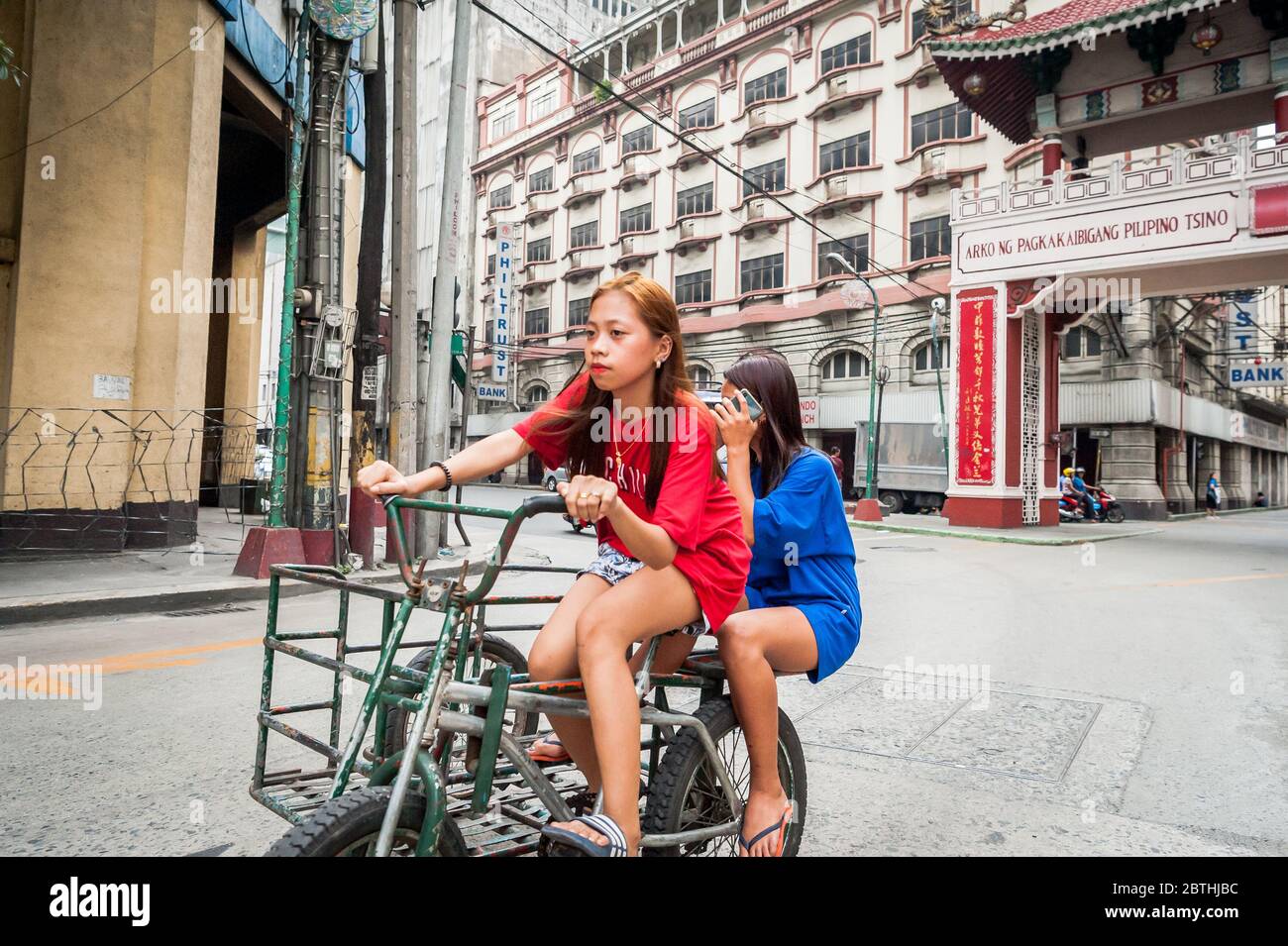 Deux jeunes filles philippines locales traversent la jonction animée de l'Arc d'amitié philippin chinois dans le quartier de Binondo Chinatown à Manille Philippines. Banque D'Images