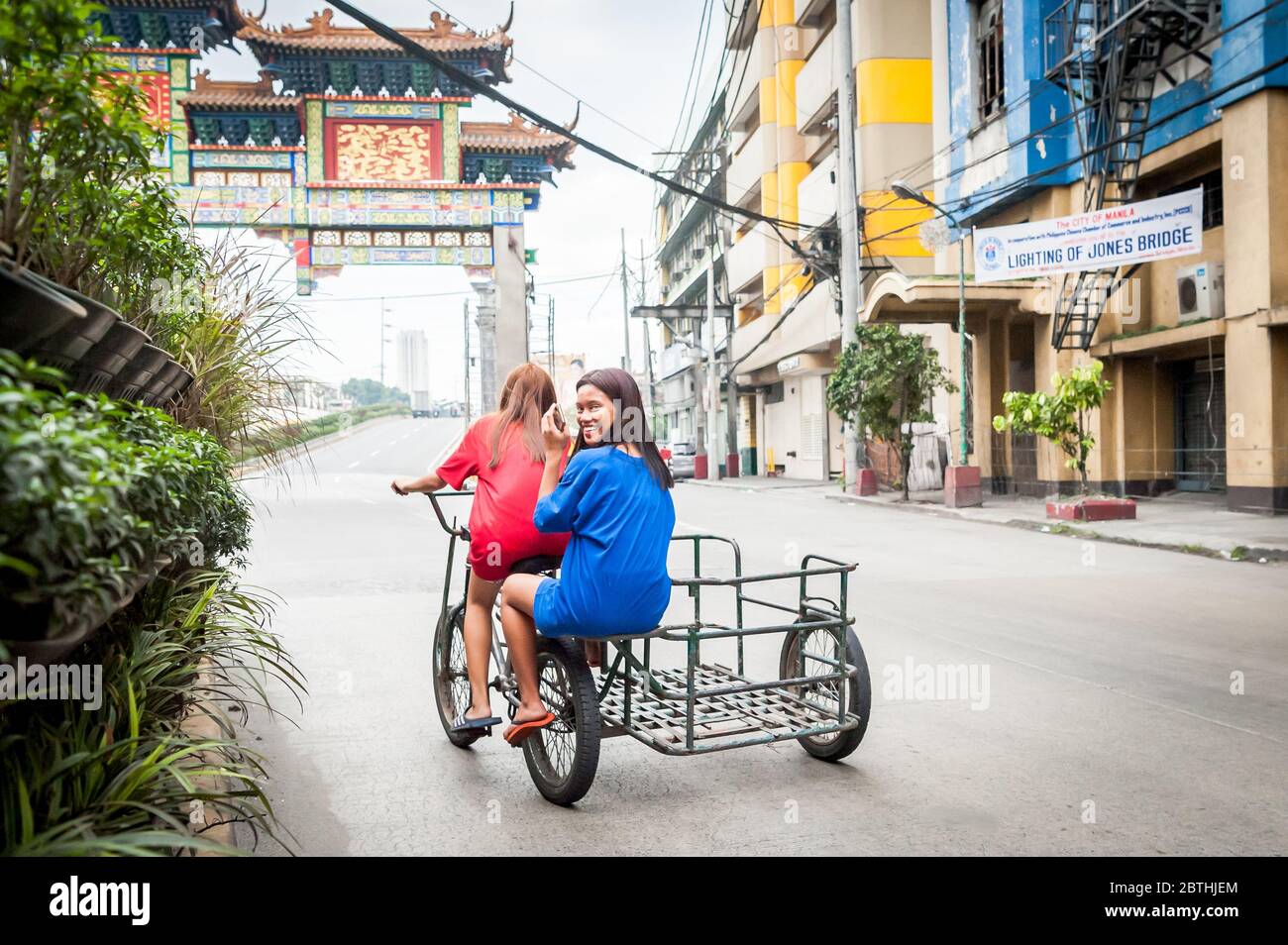 Deux jeunes filles philippines locales traversent la jonction animée de l'Arc d'amitié philippin chinois dans le quartier de Binondo Chinatown à Manille Philippines. Banque D'Images