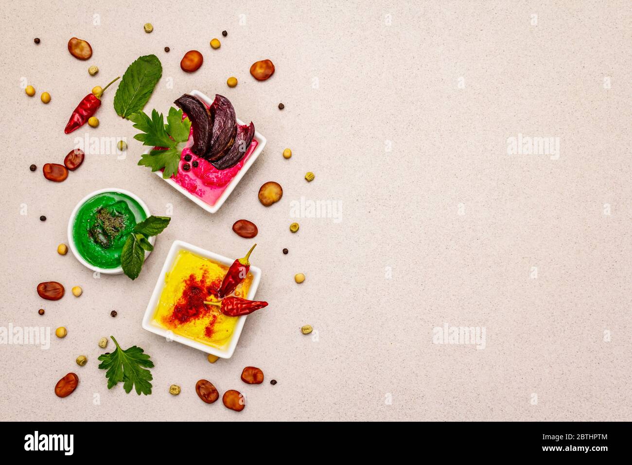 Hummus, nourriture végétalienne (végétarienne) saine. Trois types variés : classique, menthe et betterave. Haricots secs édamame, morceaux de pain pita, épices. Béton de pierre Banque D'Images