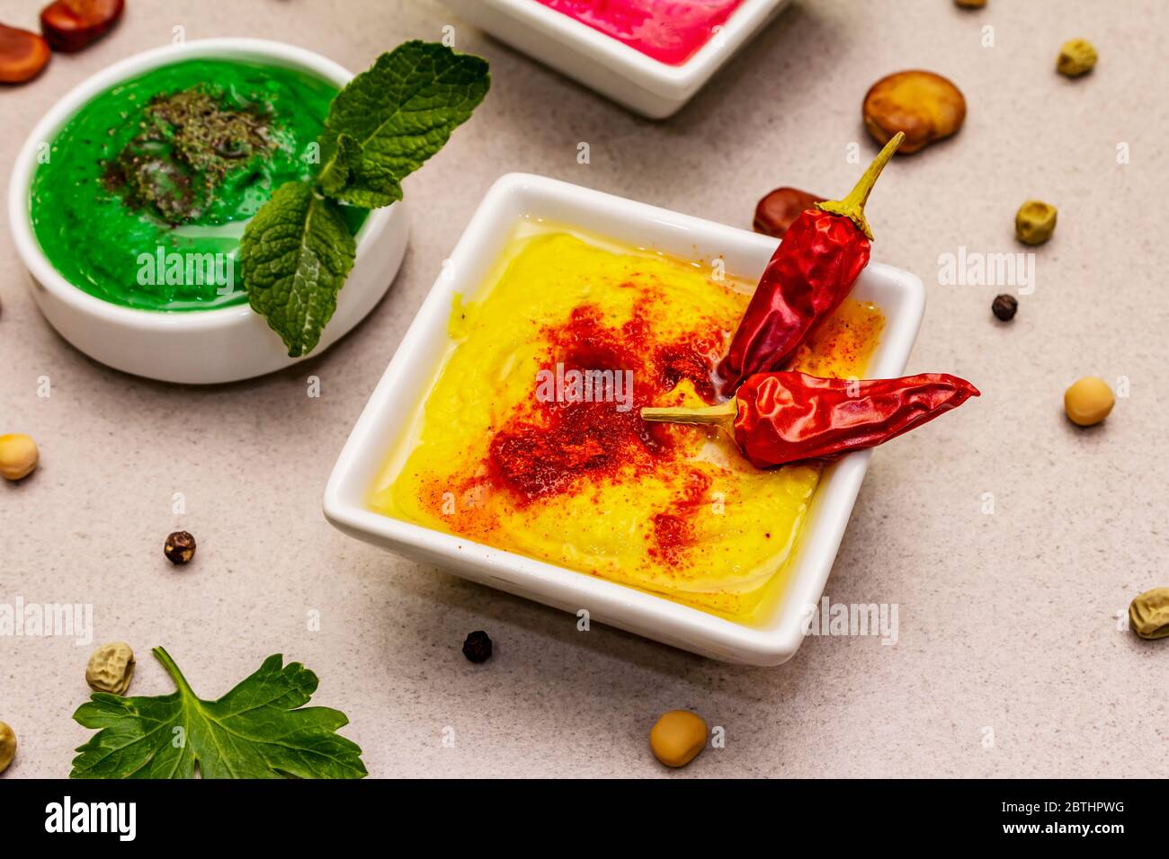 Hummus, nourriture végétalienne (végétarienne) saine. Trois types variés : classique, menthe et betterave. Haricots secs édamame, morceaux de pain pita, épices. Béton de pierre Banque D'Images