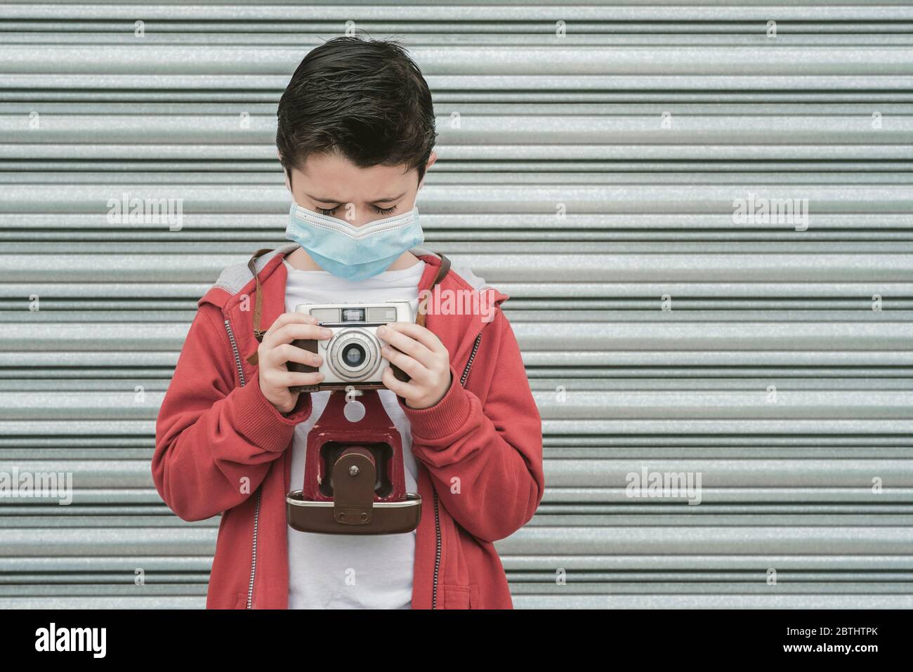 enfant avec masque médical prenez des photos avec son appareil photo extérieur Banque D'Images