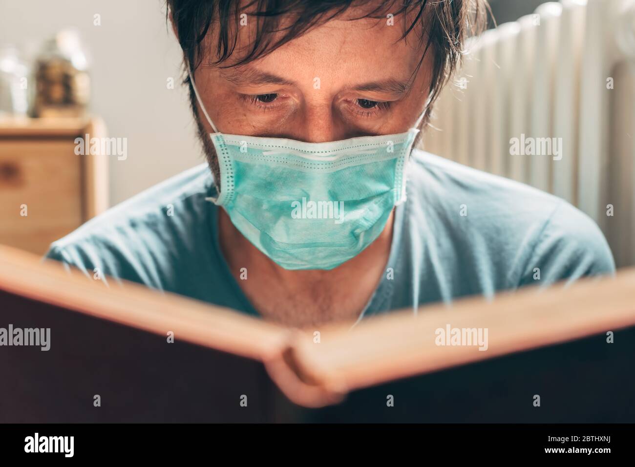 Livre de lecture de l'homme en quarantaine auto-isolée à la maison pendant la pandémie de virus Banque D'Images