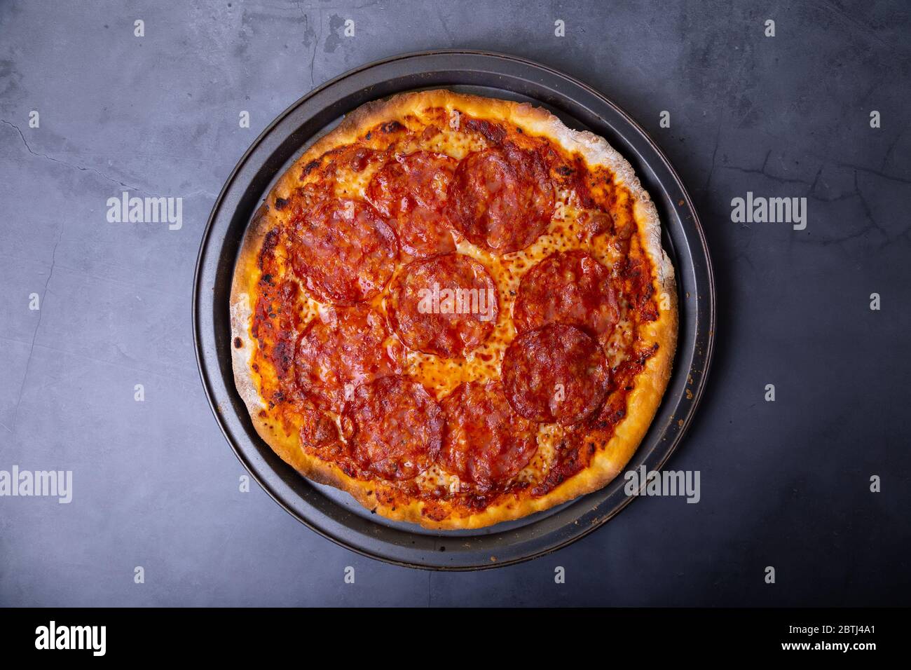Pizza avec saucisse chorizo sur fond noir. Pizza entière. Gros plan, vue de dessus. Banque D'Images