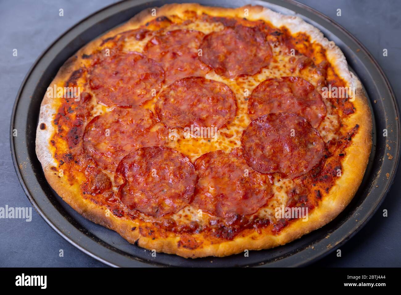 Pizza avec saucisse chorizo sur fond noir. Pizza entière. Gros plan. Banque D'Images