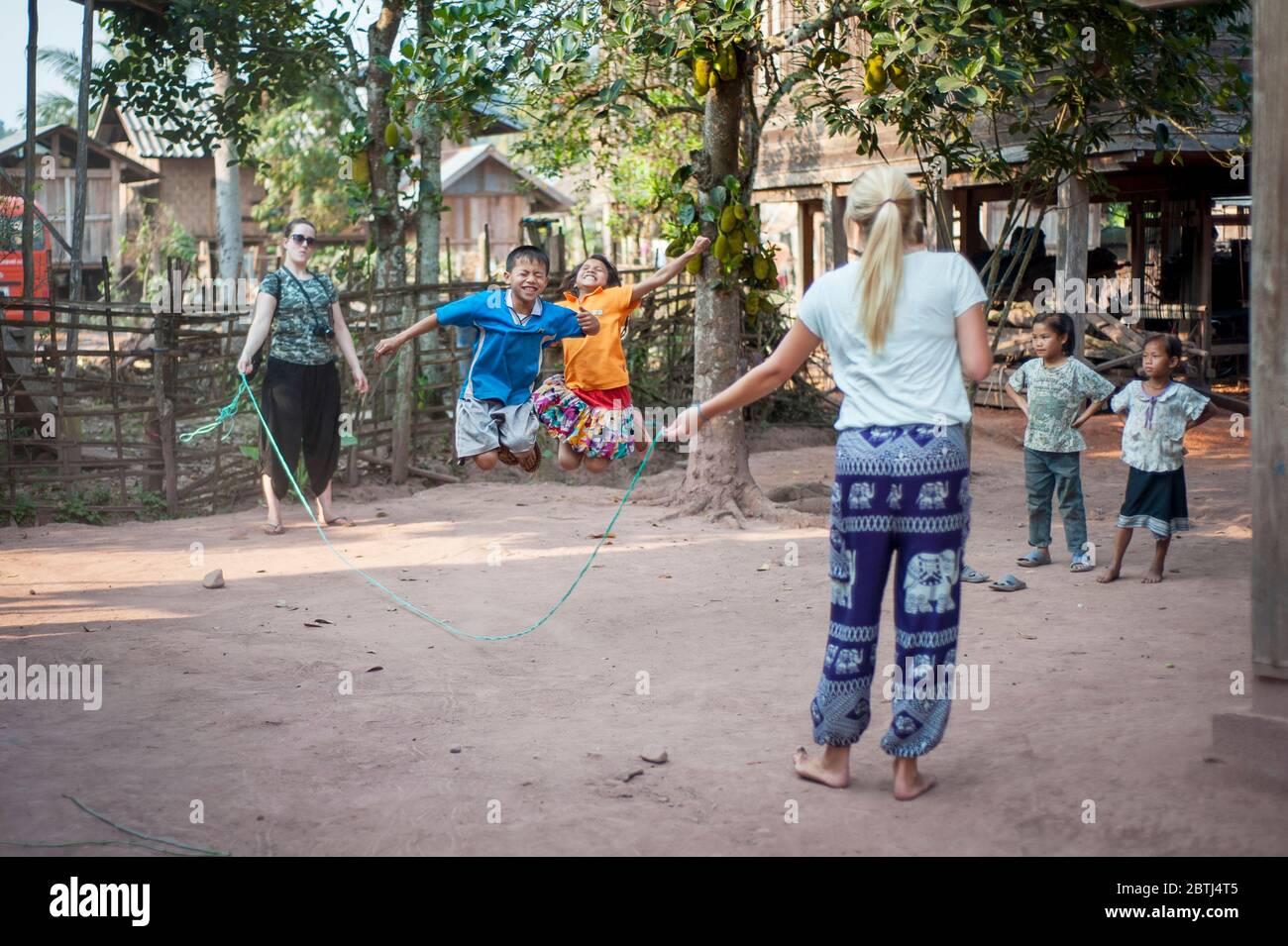 Les enfants laotiens sautant avec les visiteurs de leur village, du nord du Laos, de l'Asie du Sud-est Banque D'Images
