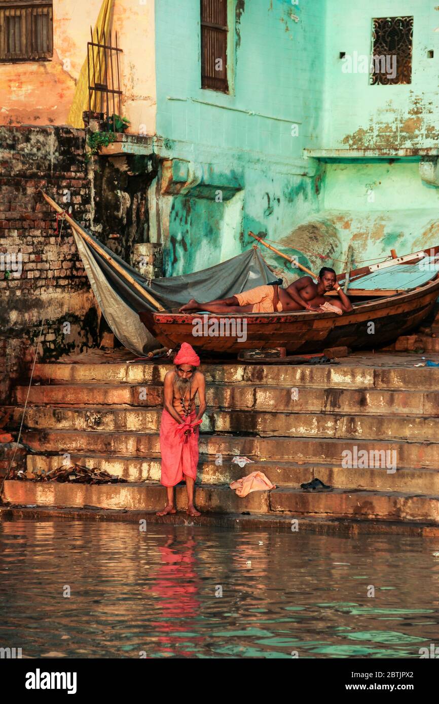 Inde, Varanasi - Etat de l'Uttar Pradesh, 31 juillet 2013. À l'aube, un homme lave ses vêtements sur le fleuve Ganges, tandis qu'un bâbord repose sur le bateau. Banque D'Images