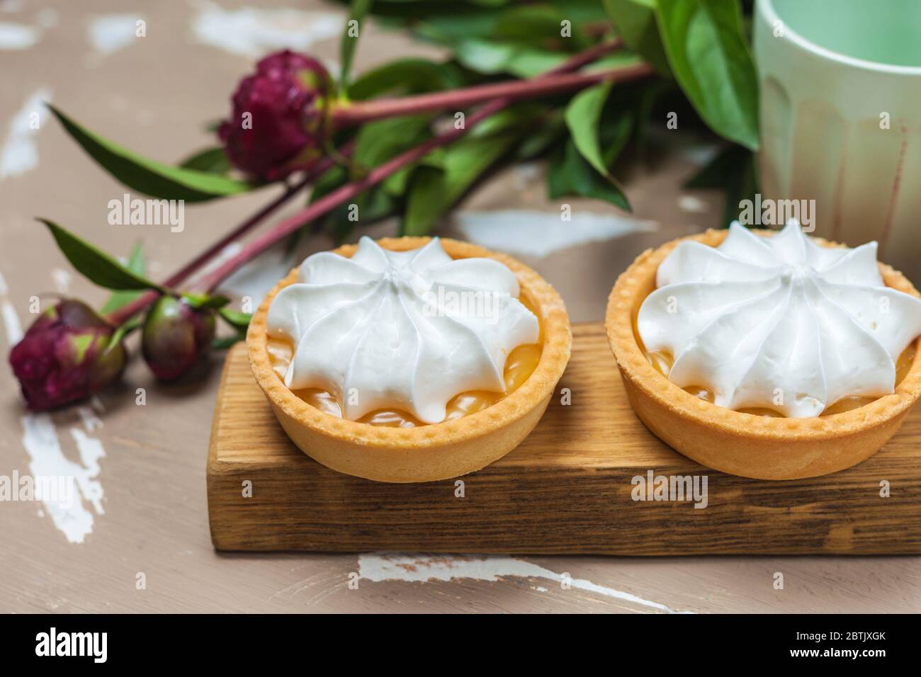 Tarte au citron. Deux gâteaux sur une assiette en bois et trois fleurs de pivoine Banque D'Images