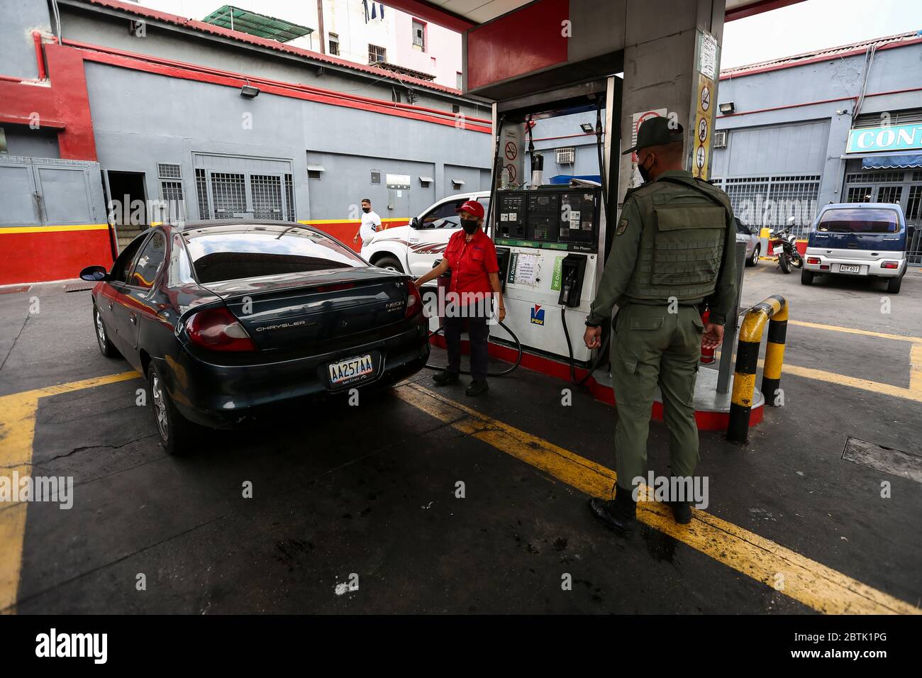 Caracas, Venezuela. 26 mai 2020. Un soldat de la Garde nationale bolivarienne vérifie les documents auprès d'une conductrice avec un garde-bouche qui fait la queue devant une station-service pendant la pénurie de carburant. Le Venezuela possède d'énormes réserves de pétrole, mais en raison d'un manque de capacité de raffinage, il a beaucoup trop peu d'essence. Selon les informations iraniennes, le premier de plusieurs pétroliers iraniens avec de l'essence pour le Venezuela a atteint le pays sud-américain. Les voitures sont actuellement autorisées à remplir jusqu'à 30 litres de carburant. Crédit : Pedro Rances Mattey/dpa/Alay Live News Banque D'Images