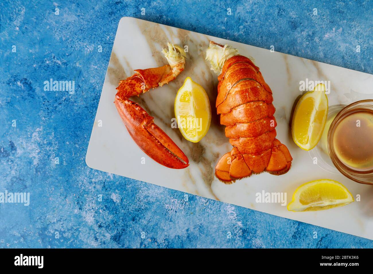 Dîner avec des morceaux de homard cuits prêts à manger dans la table avec sauce au citron et au beurre Banque D'Images