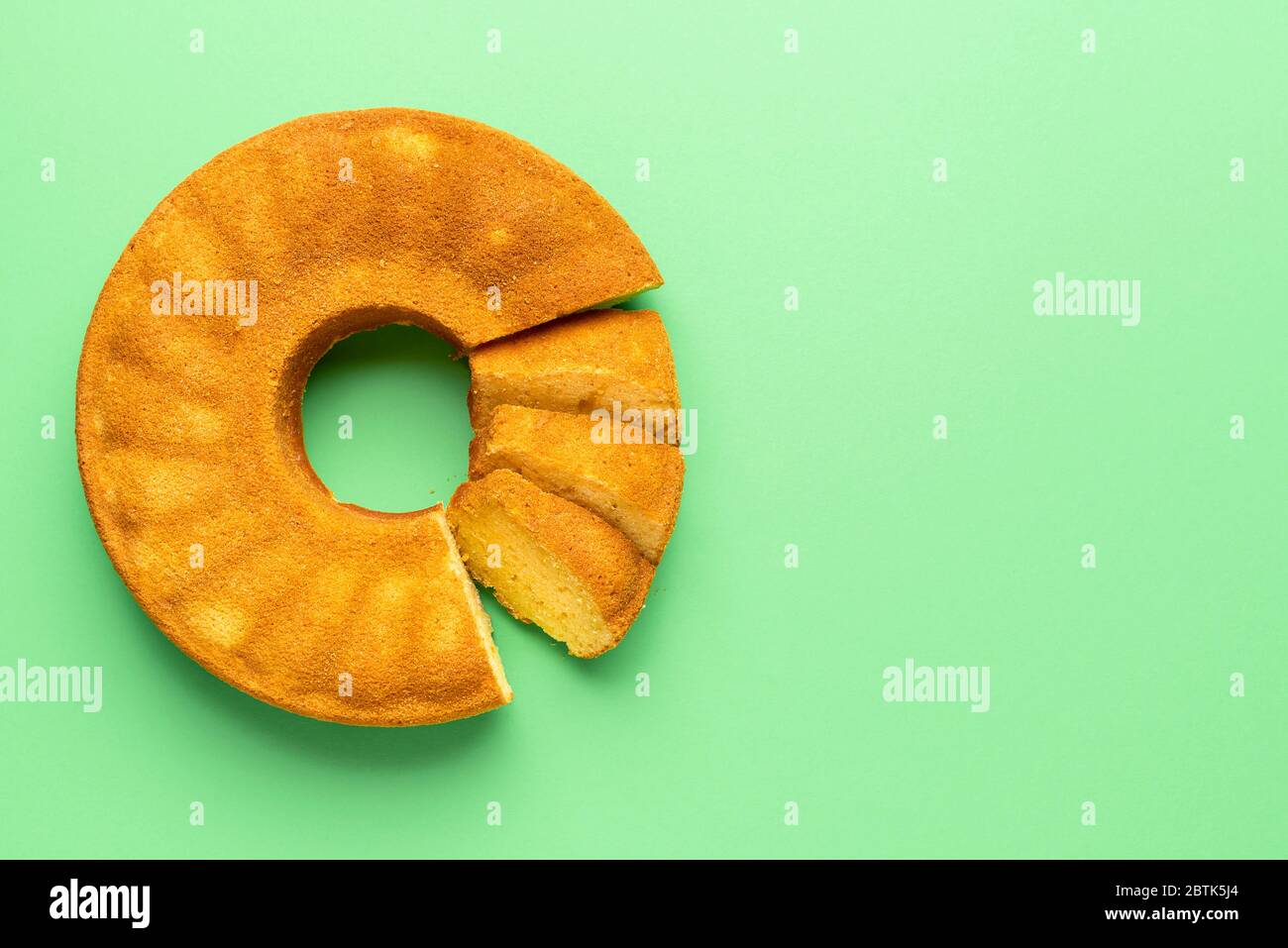 Gâteau portugais de la semoule de maïs, tranché, sur fond vert. Plat avec dessert traditionnel Festa Junina. Gâteau brésilien. Dessert de maïs. Banque D'Images