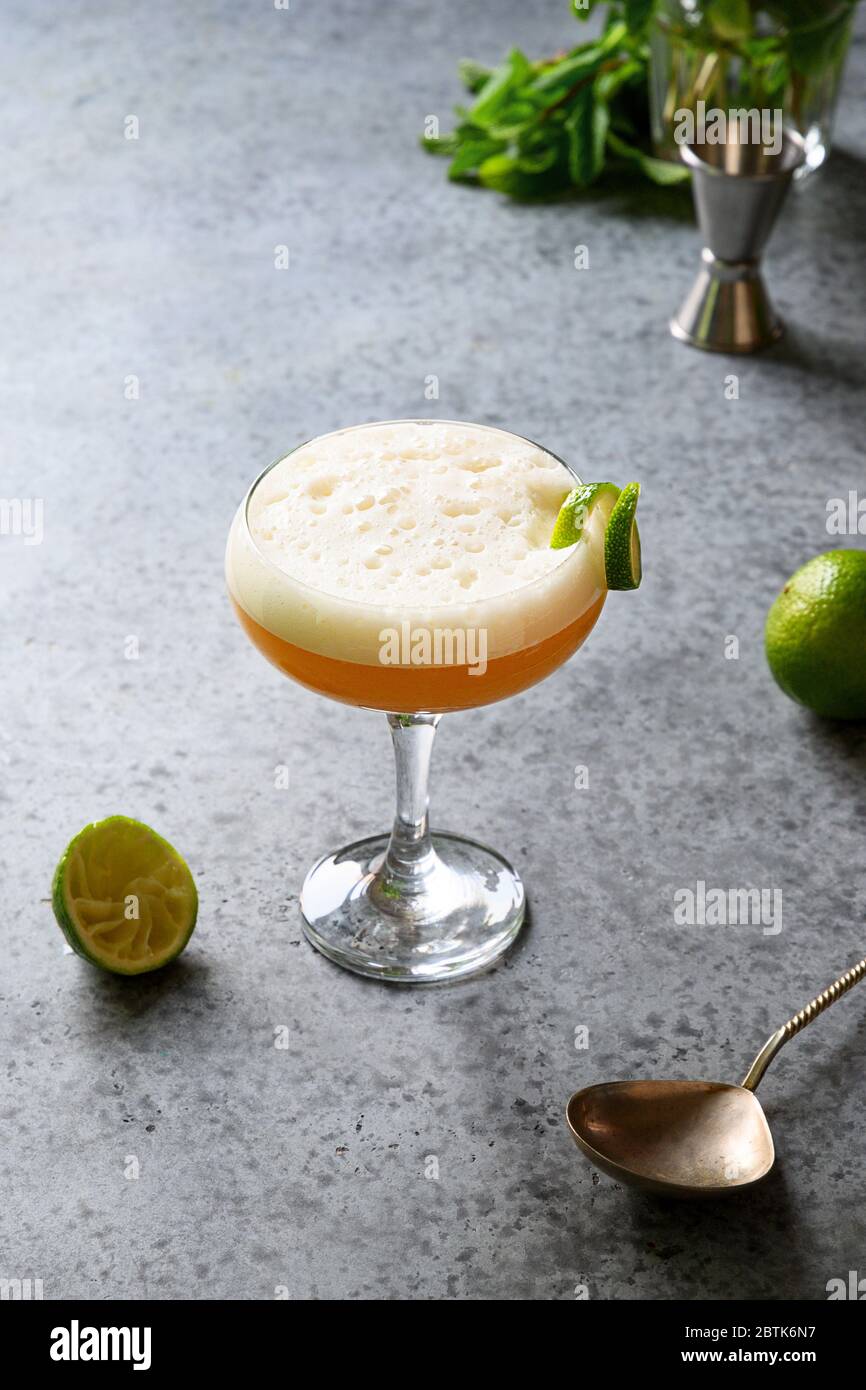 Pisco Sour cocktail - whisky au citron vert, blanc d'œuf, sirop de sucre  dans un verre sur table en pierre grise. Tir vertical Photo Stock - Alamy