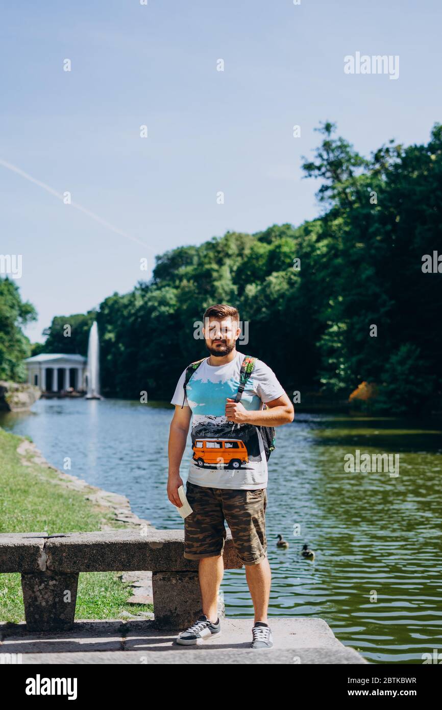Parc Sofia, Uman. Beau homme avec un sac à dos et un t-shirt sur le fond d'un beau lac. Jeune homme sur le fond du lac avec un tal Banque D'Images