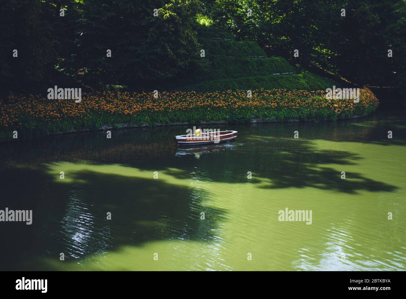 Parc Sofia, Uman. Bateau rouge-blanc sur le lac dans le parc d'été. Un homme dans un bateau navigue sur un lac dans un parc national. Le beau lac naturel est sur Banque D'Images