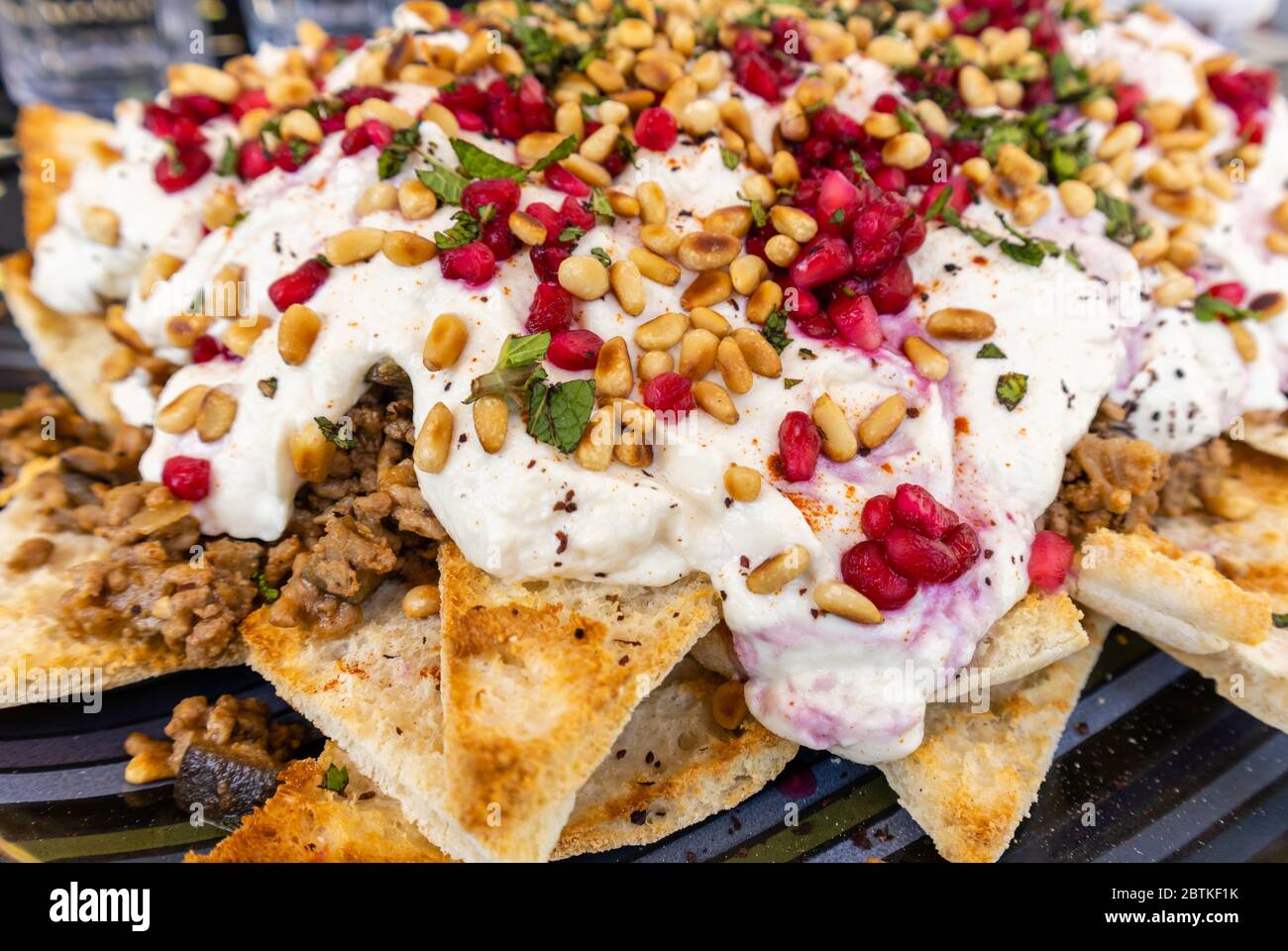 Une assiette de fatteh de bœuf et d'aubergine, un plat traditionnel du Moyen-Orient composé de morceaux de pain plat grillés, nappés d'aubergines et de bœuf et de yaourt Banque D'Images