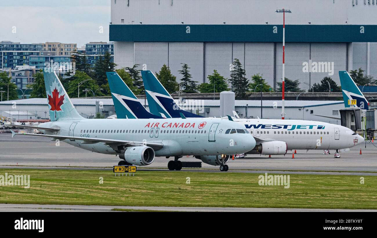 Richmond, Colombie-Britannique, Canada. 23 mai 2020. Un taxi à réaction A320 Airbus (C-FTJQ) d'Air Canada à une porte d'embarquement à l'aéroport international de Vancouver, le 23 mai 2020. En arrière-plan, les avions WestJet Airlines restent garés en raison de la réduction des déplacements aériens en raison de la pandémie COVID-19. Crédit : Bayne Stanley/ZUMA Wire/Alay Live News Banque D'Images