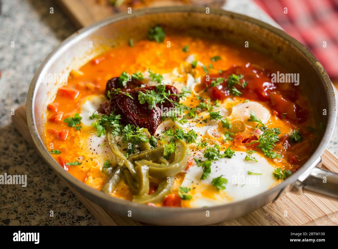 Shakshouka avec poivrons rouges et pâte de tomate, œufs, ras-el-hanout, poivrons chipotle et nopes marinés, salsa Banque D'Images