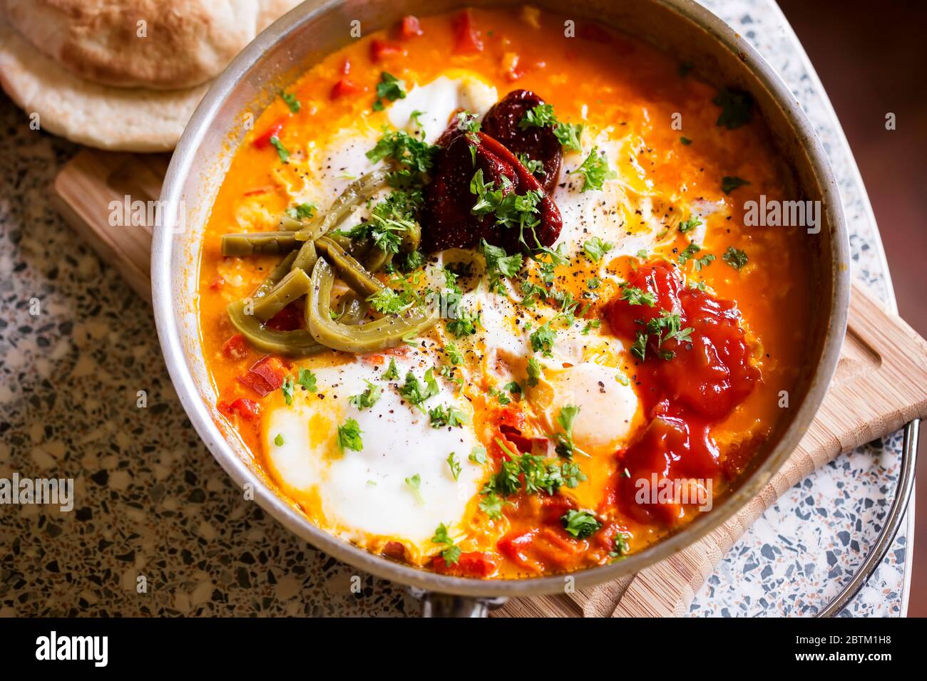 Shakshouka avec poivrons rouges et pâte de tomate, œufs, ras-el-hanout, poivrons chipotle et nopes marinés, salsa Banque D'Images