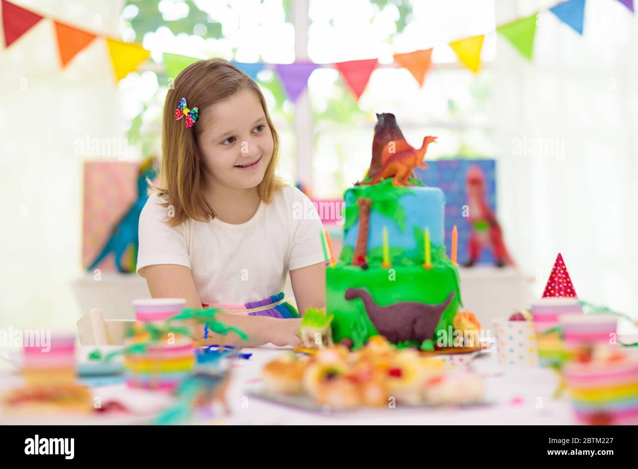 Fete D Anniversaire Pour Enfants Gateau Sur Le Theme Des Dinosaures Petites Filles Soufflant Bougies Et Ouverture De Cadeaux Evenement Enfants Decoration Pour Les Dinosaures Photo Stock Alamy