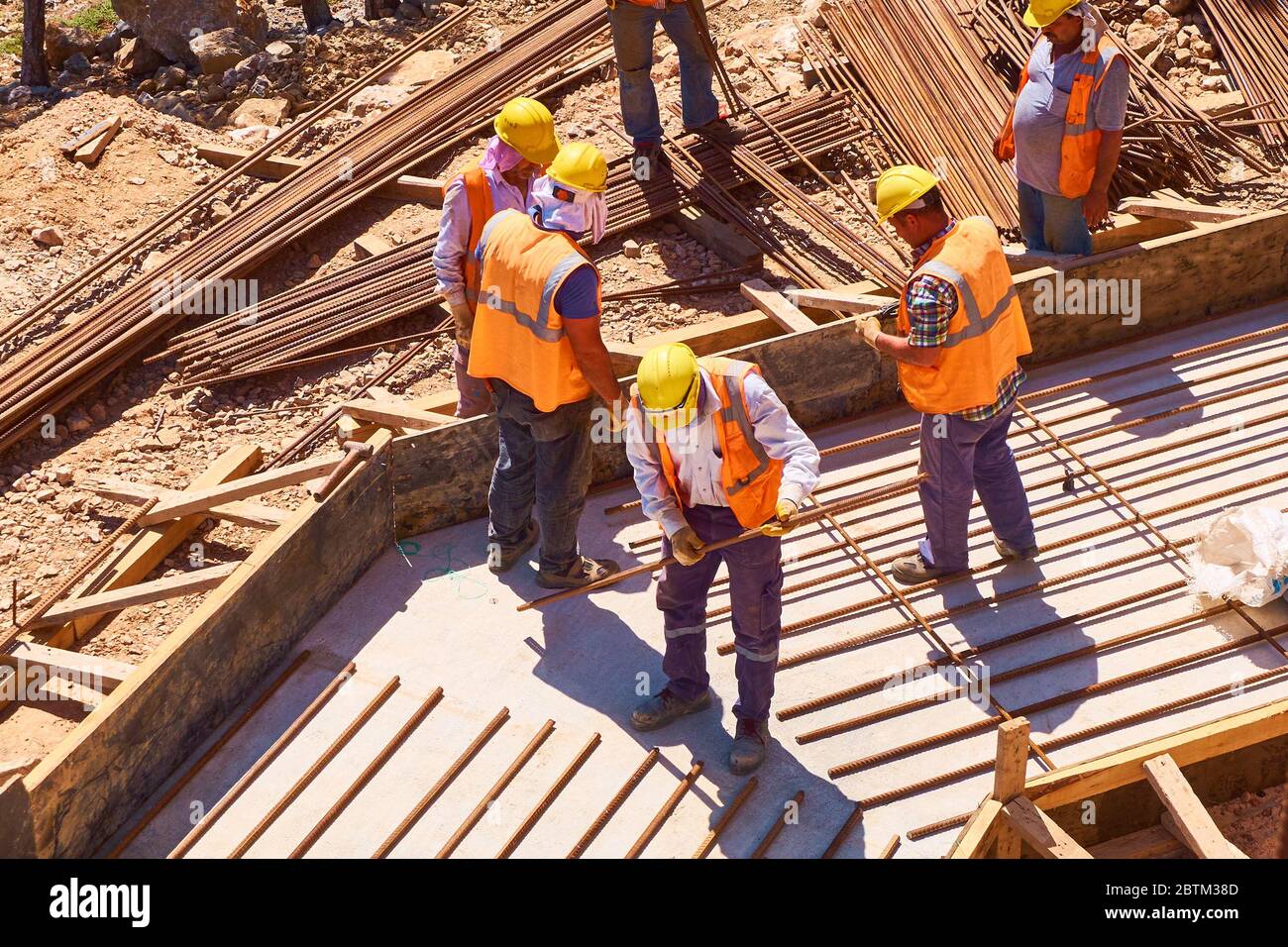 Les travailleurs construisent des plaques de fondation renforcées en béton sur le chantier de construction. Banque D'Images