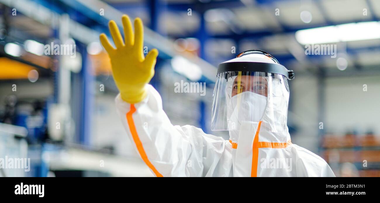 Ouvrier avec masque de protection et costume dans l'usine industrielle, salutation main geste. Banque D'Images