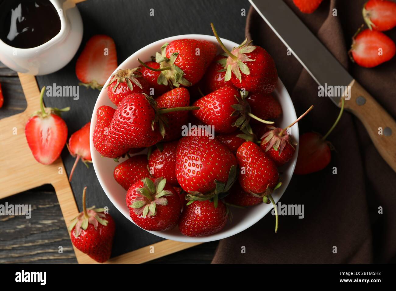 Composition avec bol de fraise savoureuse sur table en bois. Baies d'été Banque D'Images