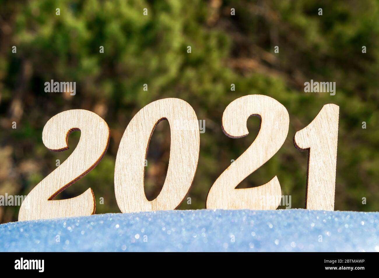 Célébration de la nouvelle année 2021. Les numéros de bois 2021 sur une surface enneigée de la forêt de vignerons. Illuminé par le soleil éclatant sur fond d'épicéa. Banque D'Images