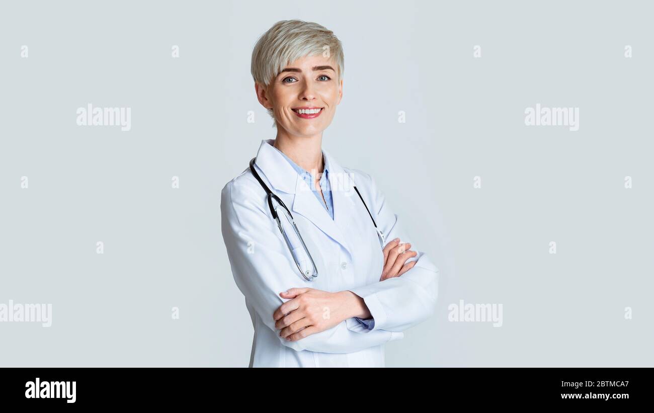 Portrait de jeune femme souriante médecin en manteau blanc avec stéthoscope, isolé sur fond clair Banque D'Images