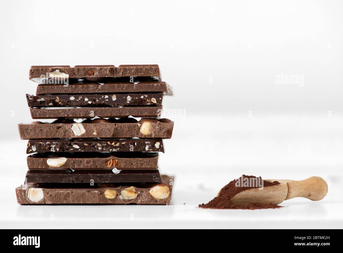 Différents types de chocolats avec noix de cacao en poudre et menthe - foyer sélectif, fond blanc Banque D'Images